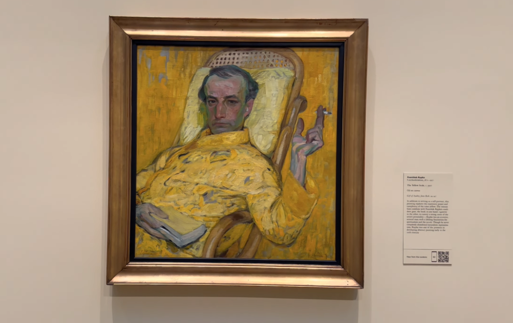 A painting of a man in a yellow robe with a stern expression, displayed in a gallery