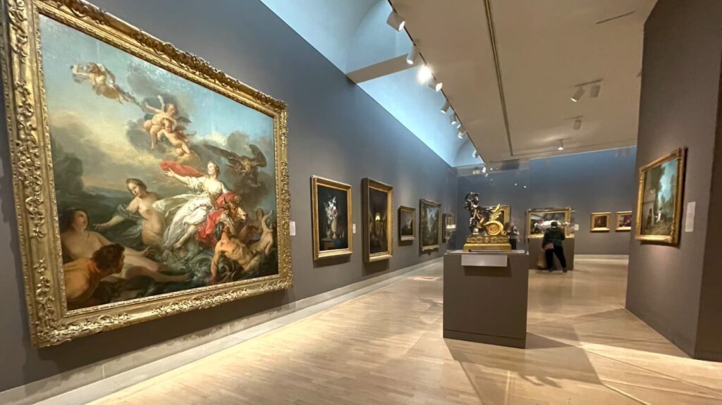 Interior of an art gallery featuring classical paintings and sculptures